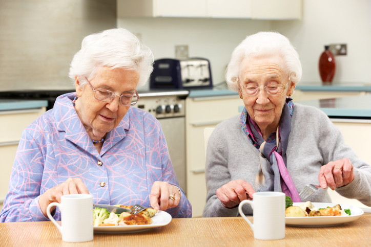 Senior friends enjoying meal in kitchen