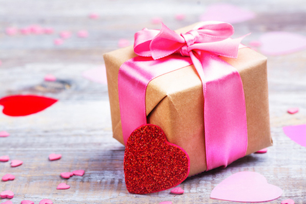Gift box with pink bow ribbon and glitter hearts on wooden rustic background