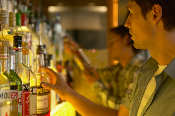 "Bartender reaching for bottle of spirits, close-up"